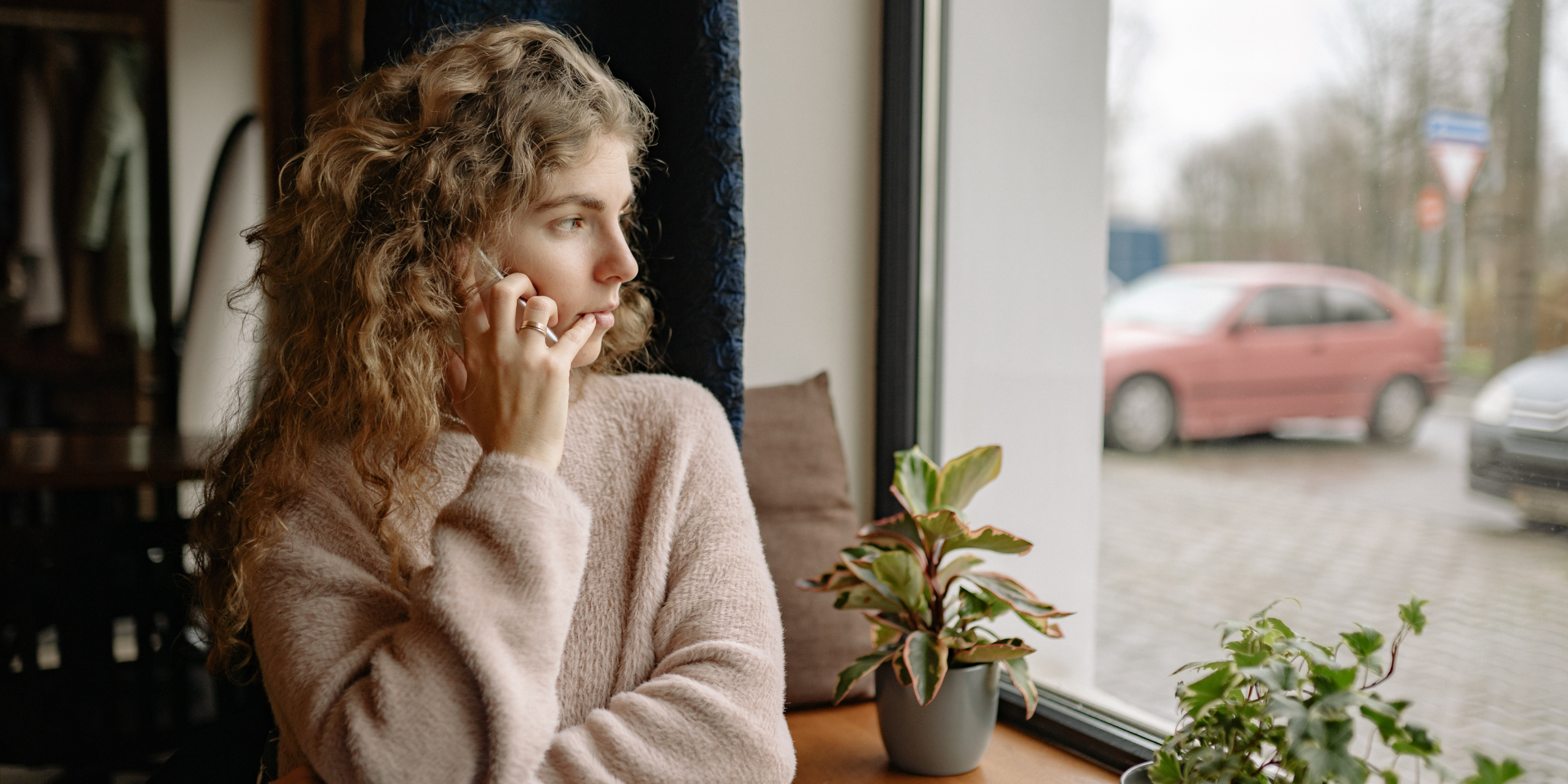 Woman sitting by a window, looking thoughtful