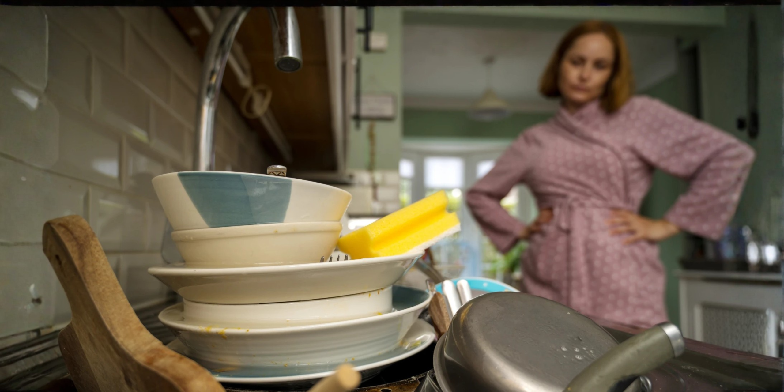 3 things off your plate Blog - Eva Rado Woman standing over a pile of dishes in the kitchen, showing the mental load many mums carry at home